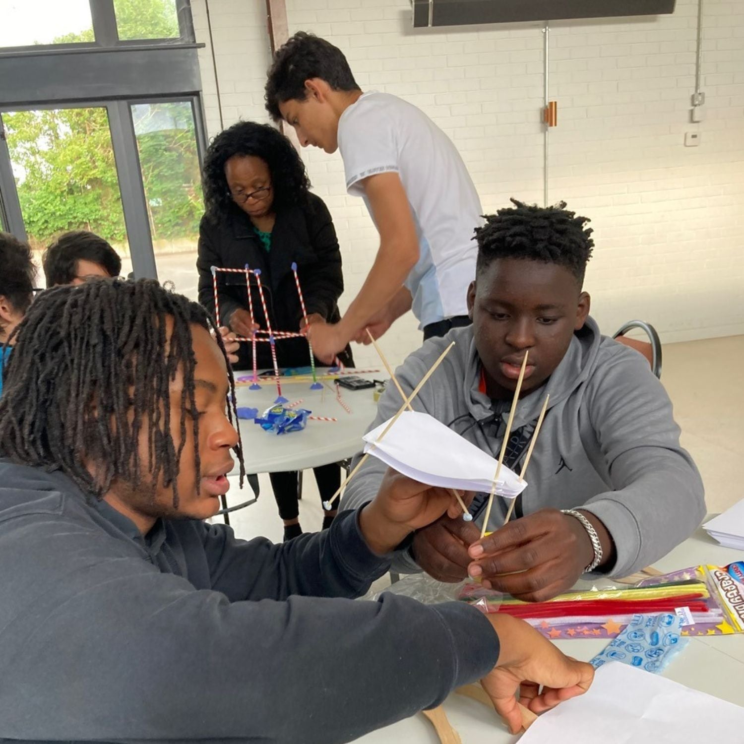 class-with-students-working-together-building-a-tall-object-using-straws-bluetack-paper-bbq-sticks-etc